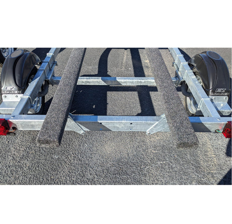 Metal boat trailer on a gravel surface showing knott axle 