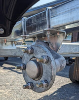 Close-up of a metal wheel hub and trailer hitch on a vehicle.