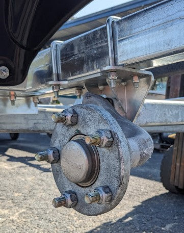 Close-up of a metal wheel hub and trailer hitch on a vehicle.